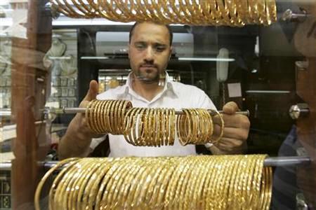 A Jordanian goldsmith holds gold bracelets at his shop in Amman.