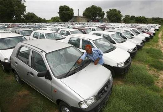 A worker adjusts the windscreen wipers of a parked Alto car at a Maruti Suzuki stockyard.