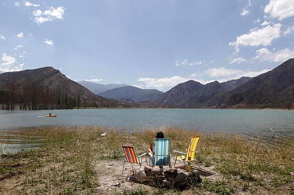 A tourist enjoys the view from the edge of the lake of the Potrerillos district.