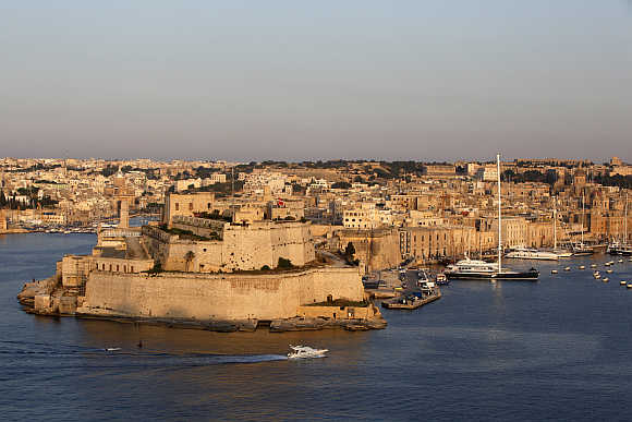 A boat sails past the medieval Fort Saint Angelo in Vittoriosa in Valletta's Grand Harbour, Malta.