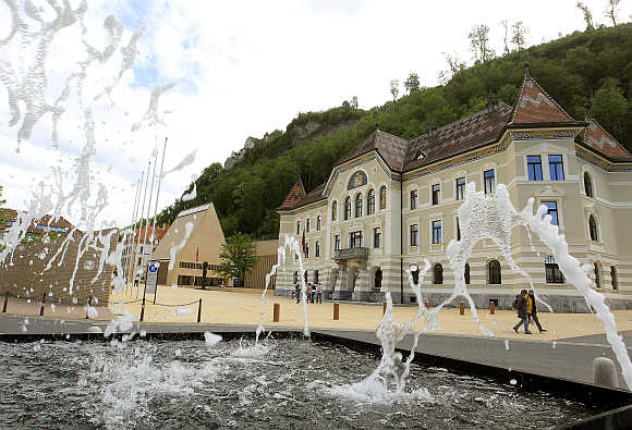 People walk past the government building, right, and the Landtag parliament, left, in Liechtenstein's capital Vaduz.