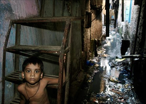 A child sits on the steps of stairs at a slum in Mumbai.