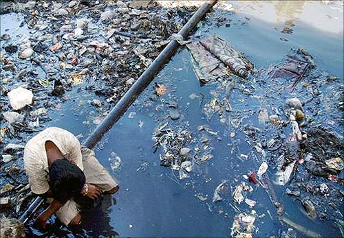 A boy rests on a pipe in a canal flowing through the slums in Mumbai.