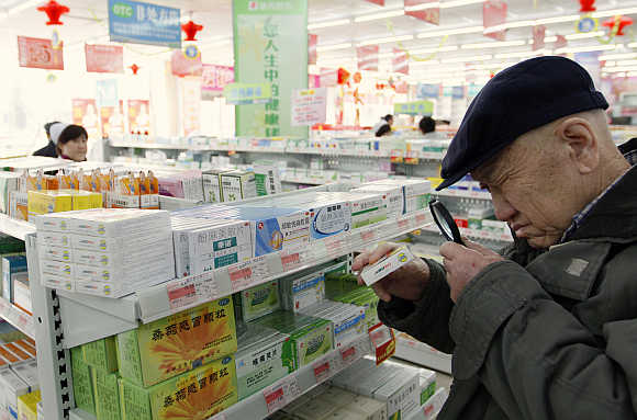 A man uses a magnifier to see the descriptions on a pack of medicine at a pharmacy in Dandong, Liaoning province, China.