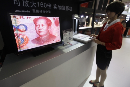 An employee operates a camera to zoom in on the image of a Chinese one-hundred yuan banknote at a production exhibition in Wuhan, Hubei province.
