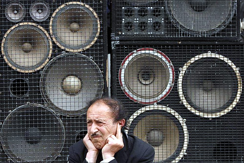 A man protects his ears as he sits in front of loud speakers during an opposition rally in central Yerevan.
