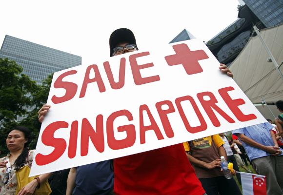 A protester holds a placard during a May Day protest against high living costs and immigration policies at Hong Lim Park in Singapore.