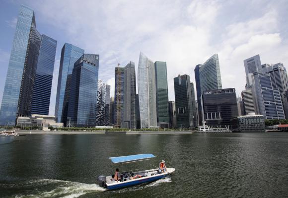 A boat manoeuvres in front of skyscrapers of the Marina Bay Financial Centre in Singapore.