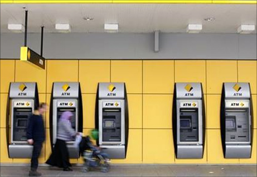 A couple walk past Commonwealth Bank automatic teller machines in Melbourne.