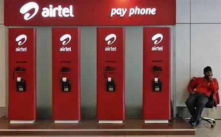 An employee sits at a Bharti Airtel public phone booth installed at the airport in New Delhi.
