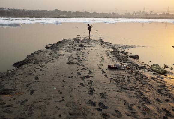 A boy searches for coins thrown by Hindu devotees in the waters of the river Yamuna.