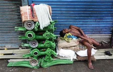 A labourer sleeps beside new iron hand pumps at an iron wholesale market in Kolkata.