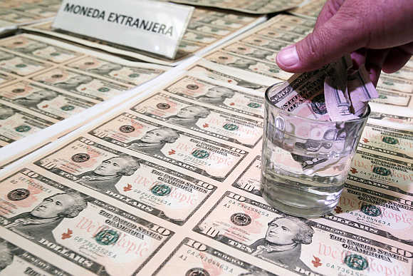 A police officer immerses a counterfeit dollar bill in liquid to show its quality during a media conference in Lima, Peru.