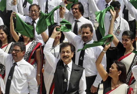 Roy (C, bottom) waves a green cloth together with his employees after singing the national anthem in Lucknow.
