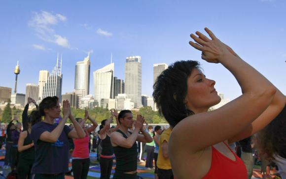 Yoga enthusiasts perform sun salutations in front of the Sydney skyline.