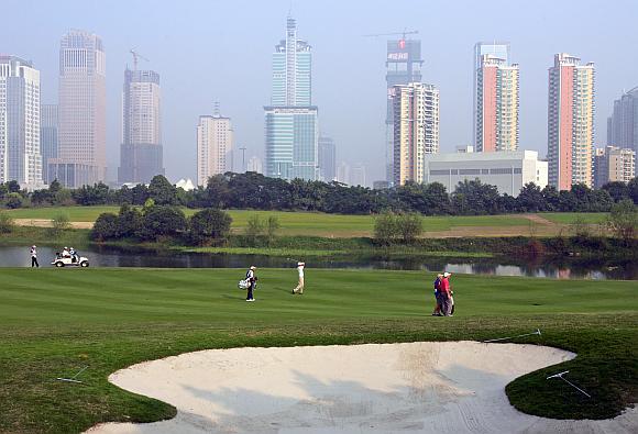 China's top golfer Zhang Lianwei (C) hits on the 14th fairway overlooking the city skyline during the third round of the $1.2 million China Open golf tournament at Shenzhen Golf Club in China's southern city of Shenzhen.