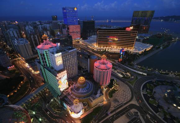 A general view of local and foreign casinos in Macau, including Hotel Lisboa (in pink) and Wynn Macau (with orange lines), in the evening.