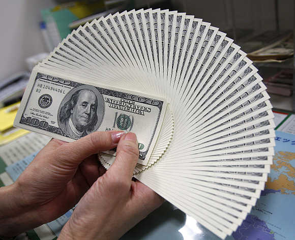 An employee of a money exchange counts US dollar notes in Tokyo, Japan.