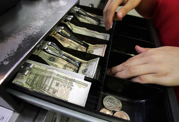 Mexican currency is seen in the cash register drawer alongside US dollars as a cashier at Pizza Patron makes change for a customer in Dallas, Texas, United States.