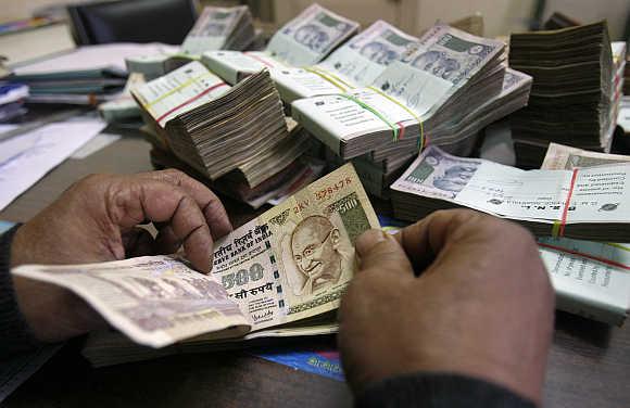 A bank employee counts rupee notes.