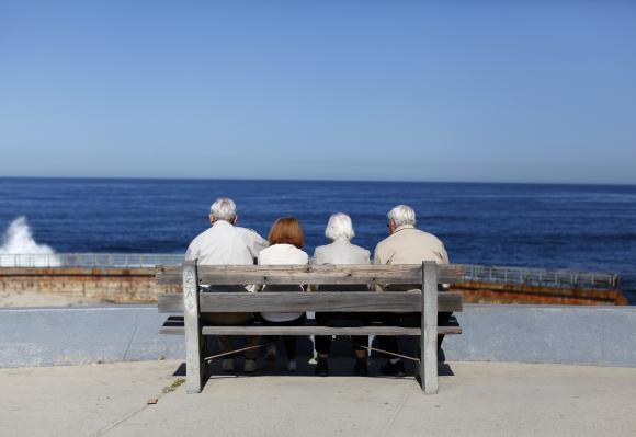 A pair of elderly couples view the ocean and waves along the beach in La Jolla, California.