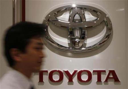 A man walks past a logo of Toyota Motor at its dealers shop.