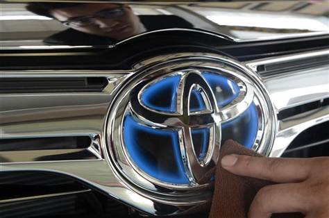 A worker cleans the logo of a Toyota car at dealership store in Taiyuan.