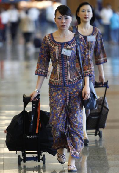 Singapore Airlines flight attendants walk through the terminal at an airport.