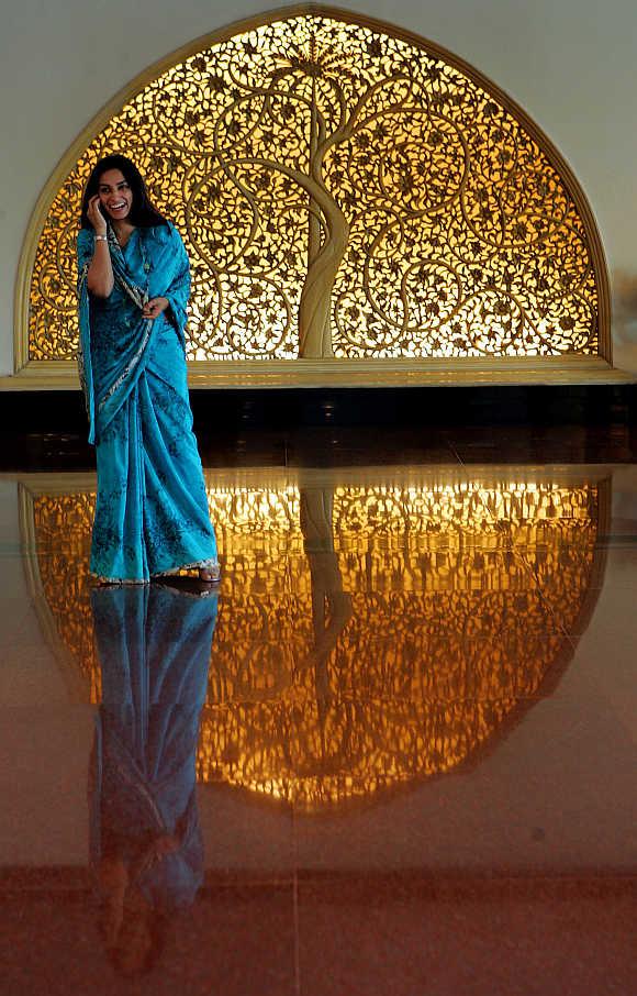  A woman talks on a mobile phone as she stands near a wood carving at a hotel lobby in New Delhi.