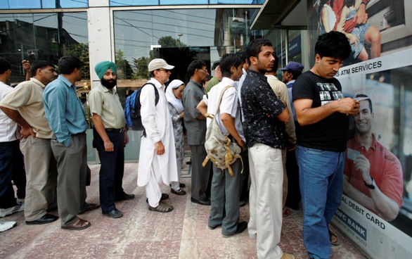 Kashmiri people wait in line outside an ATM to withdraw money in Srinagar.