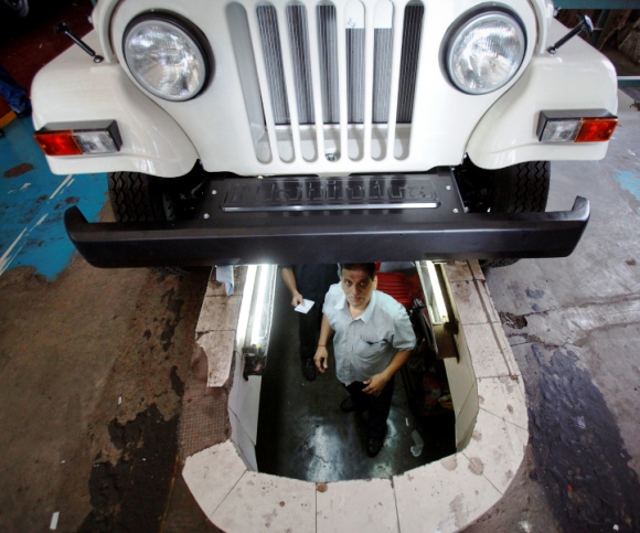 An employee looks out from a pit under an assembled Mahindra Bolero vehicle at the company's manufacturing plant on the outskirts of Mumbai.