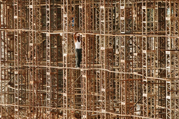 A construction worker stands on scaffolding at the site of a bridge.