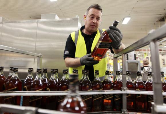 A worker looks at a bottle of Johnnie Walker whisky at the Diageo owned Shieldhall bottling plant in Glasgow, Scotland.