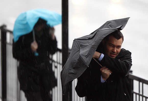 Commuters struggle through heavy rain and strong winds across London Bridge to the city of London, United Kingdom.