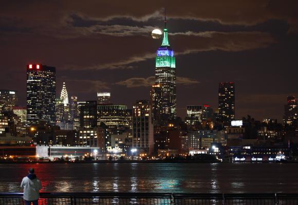 A full moon rises behind the Empire State Building in New York.