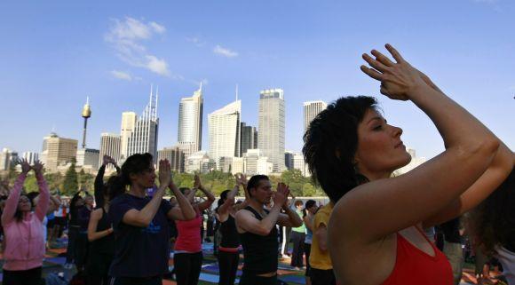 Yoga enthusiasts perform sun salutations in front of the Sydney skyline.