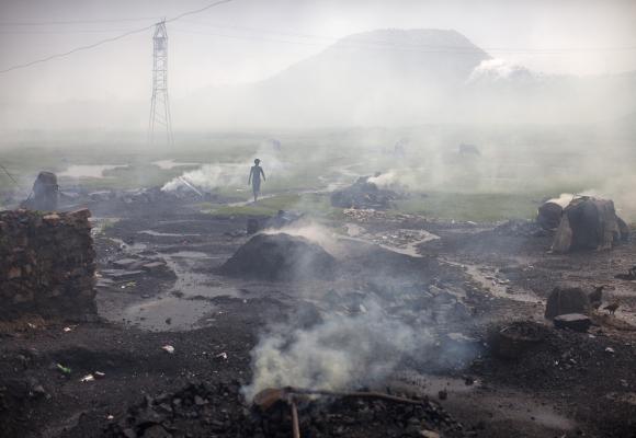 A man walks past heaps of burning coal to make it for domestic use such as for cooking purposes at Dhanbad.