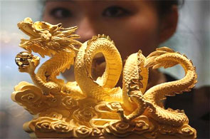 A sales representative poses behind a nine-tael 24K gold in the shape of a dragon.