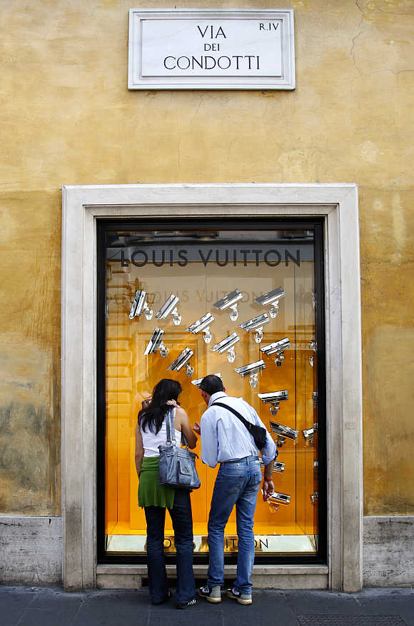 A couple looks at a window display of luxury goods maker Louis Vuitton on the shopping street of Via Condotti in central Rome, Italy.