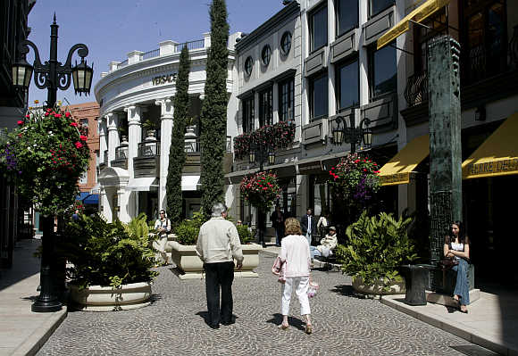 Shoppers walk towards the Versace boutique in Rodeo Drive in Beverly Hills, United States.