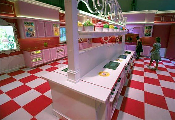 Girls watch the kitchen inside a life-size Barbie Dreamhouse.