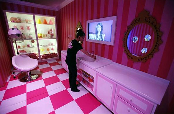 A staff poses for the photographer inside a life-size Barbie Dreamhouse.