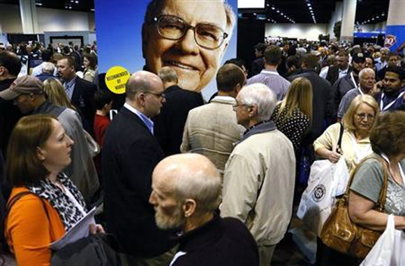 A huge picture of Berkshire Hathaway Chairman Warren Buffett looks over shareholders swarming the exhibit floor where companies owned by Berkshire display and sell their products, at the company's annual meeting in Omaha.