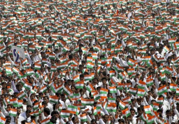 A crowd waves miniature national flags of India.