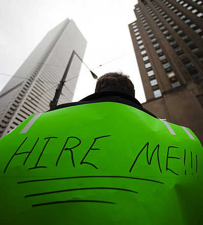 A man, with a sign strapped to his back, uses a megaphone to attract the attention of potential employers as he hands out resumes on Bay Street in the financial district in Toronto, Canada.