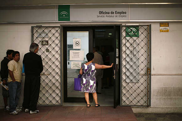A woman holds a door as she waits in line to enter a government job centre in Marbella, southern Spain.