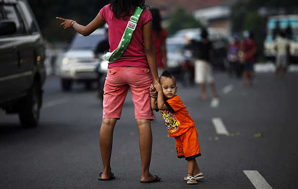 A jobless mother holds her child as she offers to be a 'car jockey' in a main street in Jakarta. Many unemployed Indonesians find work as 'car jockeys', for which they are paid around $1.50 to be car passengers, allowing the driver to use a lane dedicated to cars carrying three or more passengers.
