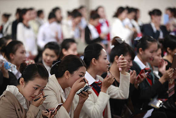 Women apply make-up as they wait during the job fair for China Eastern Airlines flight attendants in Shanghai, China.