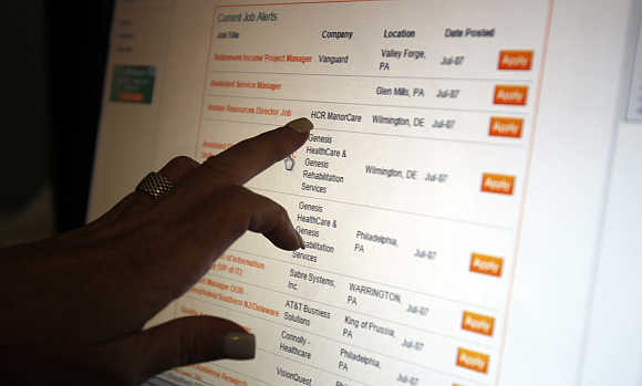A woman points to a job listing on an employment website at her residence in Sewell, New Jersey, United States.