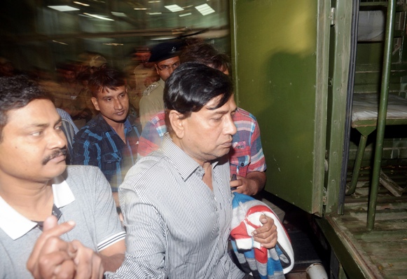 Police officers escort Chit-fund company Saradha Group's Chairman Sudipta Sen (R) to a police van outside the airport on his arrival in Kolkata.